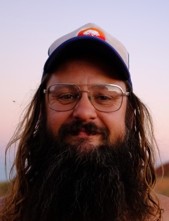 Man with beard wearing glasses and baseball cap.