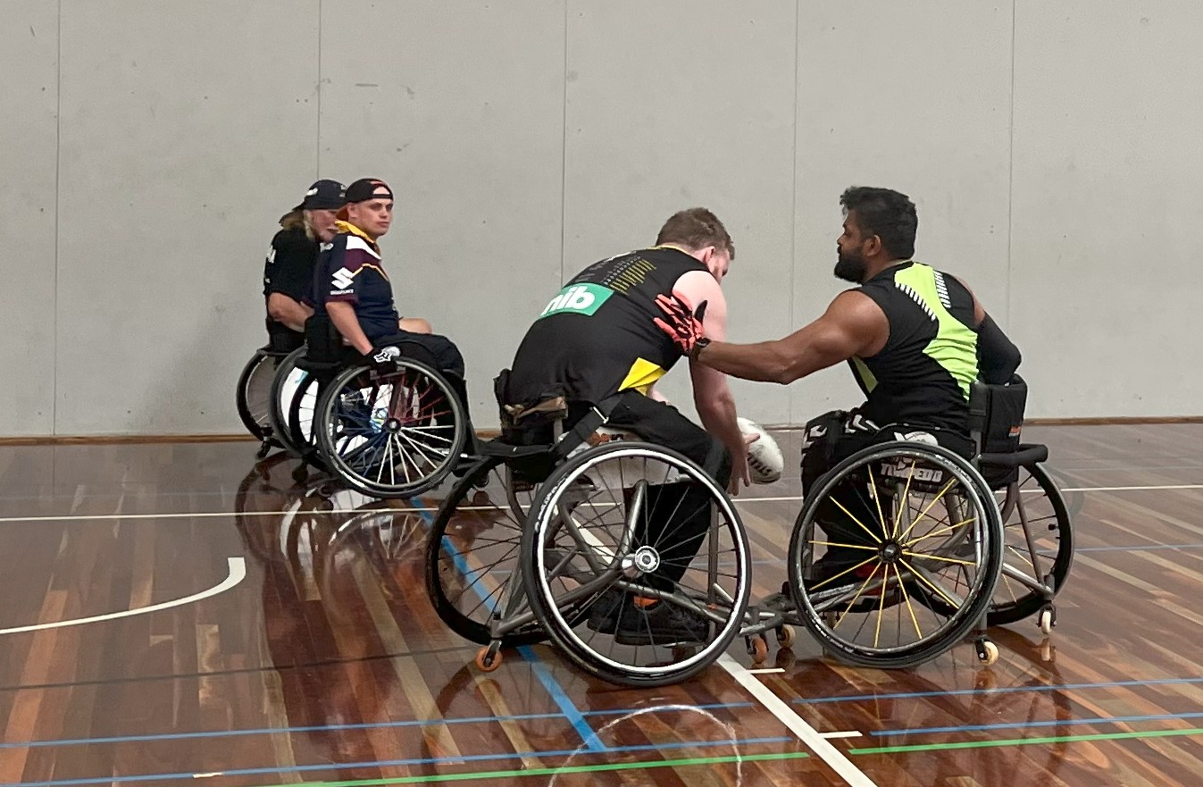 Group of men in wheelchairs on basketball court playing wheelchair rugby league